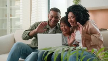 Afrikalı ebeveynler mutlu anne ve baba Kafkas oğlan çocuğu bilgisayarında uzak iletişim uygulaması kullanıyor. Çok ırklı anne ve baba ve küçük çocuk internette dedelerini selamlıyorlar.