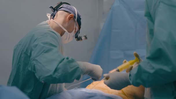 医師の医師の医師外科医は 患者の腹部医療から脂肪をポンピング看護師の手の内視鏡装置シリンジを使用して 外科リポソクション腹部操作を実行します — ストック動画
