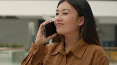 Asyalı iş kadını gülümsüyor Çinli kız iş kadını iş kadını işveren mutlu Koreli iş kadını cep telefonuyla konuşuyor akıllı telefondan konuş ofiste arkadaşça sohbet et