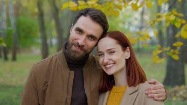 快乐微笑积极无忧无虑的白种人男人女人丈夫女朋友爱在户外约会 天生一对微笑着拥抱看着秋天公园里的相机浪漫地在一起黄叶 — 图库视频影像