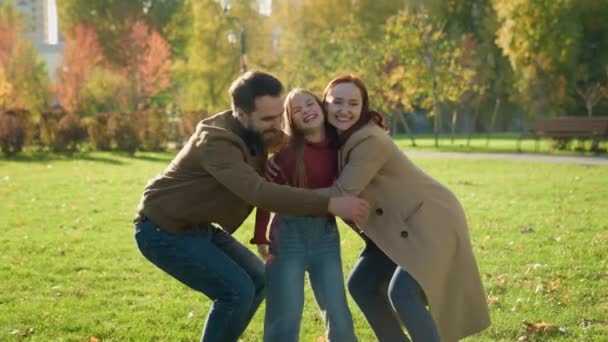 カカシアの幸せな愛する家族の父親の両親と娘の子供のガールは笑顔で抱き合って笑い 屋外の晴れた秋の公園で抱擁するかわいい抱擁を愛する子育て週末 — ストック動画