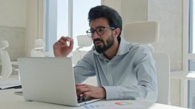 Hüsrana uğramış Arap Müslüman erkek işadamı erkek işçi müdürü, ofis stresi probleminde dizüstü bilgisayara bakan Hintli iş adamının iflasın eşiğinde olduğunu vurguladı.