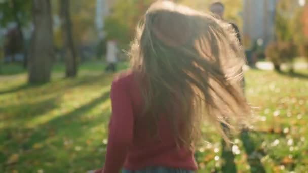 秋の日当たりの良い公園の両親の娘でコーカサスケアフリー家族 パパに走っている娘 幸せな子供ガール 楽しいラン パパキャッチリフト 屋外で一緒に遊ぶ 週末のハグアクティブゲーム — ストック動画