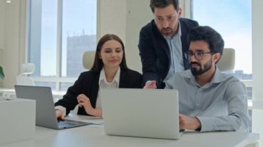 Ofiste dizüstü bilgisayarda çalışan çeşitli takım arkadaşları erkek iş koçu danışman patron işadamı çalışanlara bilgisayar eğitimi yeni işçiler ve stajyerlerin veri projesini kontrol etmede yardımcı oluyor.