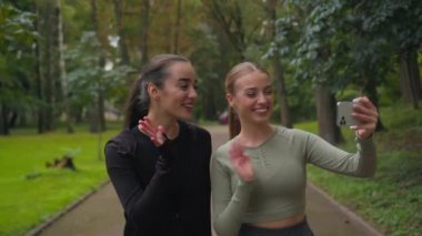 İki mutlu Kafkas sporcu kız blogu kadınları etkiledi. Cep telefonlarına el sallayan kadınlar. Video blogu sağlıklı yaşam tarzı çalışmaları.