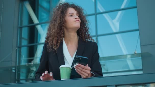 テラスでビジネスウーマンオフィス従業員がコーヒーを飲み 女性ビジネスウーマンが都市で会うのを待っている不満の若い女性が携帯電話のチェックタイムを見ています — ストック動画