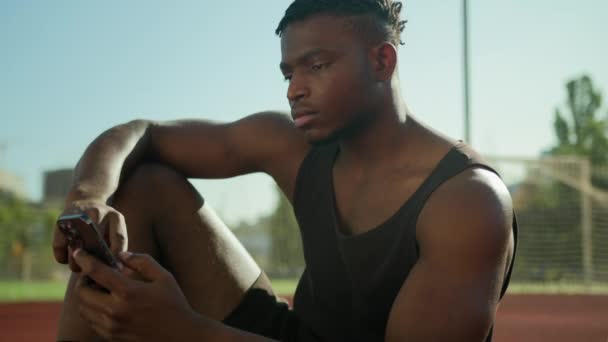 Afroamerykanin Mężczyzna Męski Sportowiec Niezadowolony Zmęczony Przewijanie Telefon Komórkowy Zrelaksować — Wideo stockowe