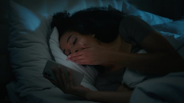 非洲裔美国女孩博客写手躺在床上沉溺于手机社交网络中睡前昏昏欲睡的疲倦女人打呵欠 在卧室里用智能手机小玩意翻滚媒体深夜失眠 — 图库视频影像