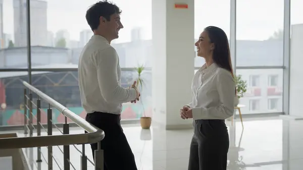 Businessman and businesswoman talking laughing in company hall corporate friendship business colleagues friends partners coworkers man woman talk friendly conversation in office lobby coworking break