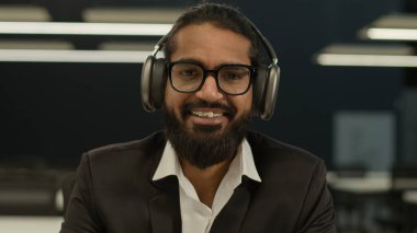 Hintli Arap adam girişimci erkek öğrenci stajyer öğrenci danışman danışman iş adamı. Not defterine notlar yazıyor. İnternette derste kulaklıkla müzik dinliyor.