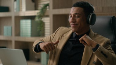 Rahat, Afrikalı Afrikalı, Amerikalı, girişimci, erkek, iş adamı, dizüstü bilgisayarlı, kulaklıklı müzik dinliyor, dinleniyor, ofis işi yapıyor, ara veriyor, dans ediyor, şarkıların tadını çıkarıyor, gülümsüyor, eğlenceli dans ediyor.