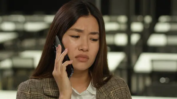Asian girl student indoors listening bad news mobile phone call worry sad upset failure frustrated Korean business woman Japanese businesswoman Chinese female in office company talk smartphone problem