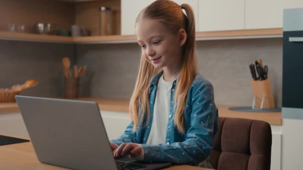 ホームキッチンでラップトップを使用して身に着けている白人十代の少女十代の子供の娘は ソーシャルメディアアプリでサーフィンを学ぶコンピュータ距離学習の学生を焦点を当てました — ストック動画