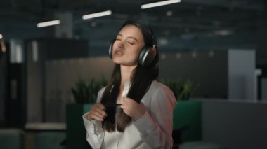Kafkasyalı iş kadını, işveren, ofis çalışanı, iş kadını, yönetici, iş yerinde kulaklıkla müzik dinliyor, şarkı söylüyor, mola veriyor.