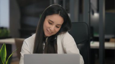 Gülümseyen mutlu Kafkasyalı iş kadını ofis çalışanı bilgisayarda yazı yazan cep telefonu iş kadını işveren kadın işveren müşteriye danışır ciddi konuşma akıllı telefon çoklu görev