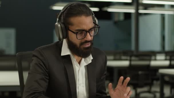 ヘッドフォンでインドのビジネスマン アラビアのビジネスマン ビデオ会議ノートパソコン話す交渉会社の通信ウェブカムラップトップコンピュータ男性リクルーターのインタビュー オフィスで遠く離れたオンライン — ストック動画