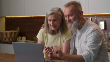 Mutlu aile yaşlı çift dizüstü bilgisayar kullanıyor markette yemek siparişi veriyor markette, süpermarkette ev eşyaları alıyor ev mutfağında internetten alışveriş yapan kadın ortası e-ticaret yapıyor.
