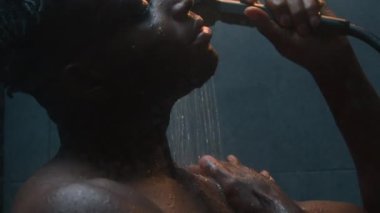 Afrika kökenli Amerikalı erkek Etnik Yıkanma Modern koyu banyoda erkek duş alıyor Sıcak su döküyor Vücut bakımı sonrası dinleniyor Vücut temizleme jeli temizleme jeli sabah köpüğü