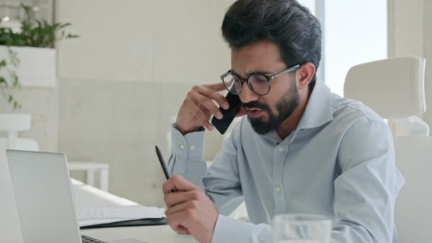 Busy Arabian インドのイスラム教徒男性成功した起業家雇用主 Ceo 最高経営責任者 ビジネスマン ラップトップコンサルタント クライアントビジネスディスカッションを使用してオフィスの職場で携帯電話を話す — ストック動画