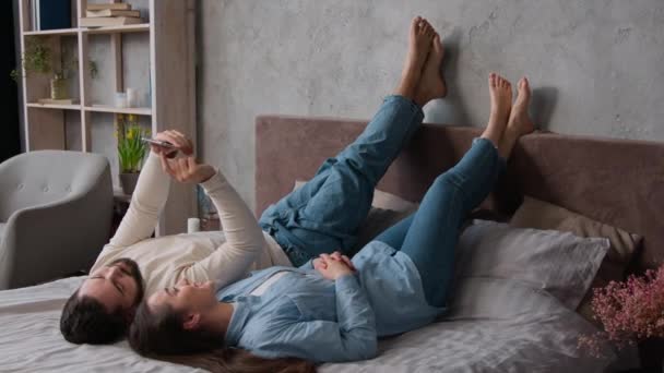Carefree 코카서스 커플은 스마트 가제트를 사용하여 침대에서 휴식을 즐기는 남성과 — 비디오