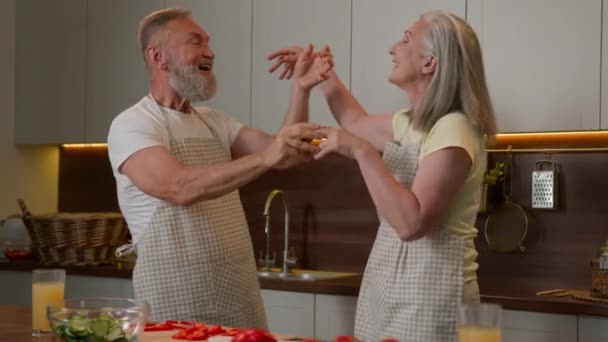 美满幸福的白种人老夫老妻退休的家庭男女在厨房里跳舞拥抱庆祝结婚周年的老年人满意的爷爷和奶奶的关系拥抱结合浪漫的舞蹈 — 图库视频影像
