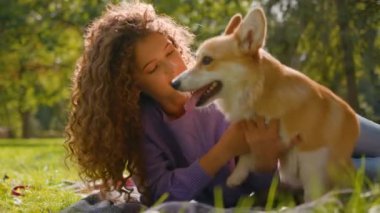 Mutlu kadın öpüşme oyunu oynuyor Galli Corgi köpeği parkta birlikte eğleniyor neşeli beyaz kız sahibi yaz şehrinde sevimli köpek yavrusuyla oynuyor arkadaşlığı seviyor insan ve evcil hayvanları seviyor