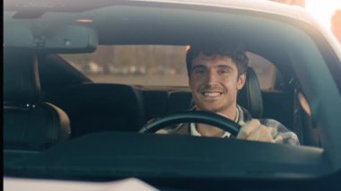 Beyaz tenli, yakışıklı, güler yüzlü iş adamı modern elektrikli otomobilde oturuyor şehir seyahatinde mutlu erkek sürücü sürücü, kiralık araç kullanıyor lüks otomobil satın alıyor.