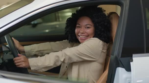 ハッピー アフリカ系アメリカ人女性クライアント クライアント ビジネスウーマン 自動車を購入する 夢豪華な電気自動車 座ってショールームのディーラー ストアで新しい輸送をテスト 女性の運転車 — ストック動画