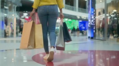 Arkaya bakan kadın alışveriş merkezinde çanta taşıyor kıyafet alışverişi yapıyor butik mağazası alışverişi yapıyor müşteri satın alıyor tanınmayan moda indirimli hayat tarzı indirimli tüketici kız müşterisi