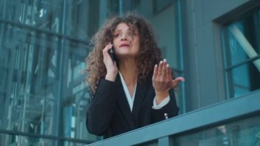 Kızgın Kafkasyalı öfkeli kızgın iş kadını patron cep telefonunun şehirde konuştuğunu savunuyor agresif genç iş kadını terasta bağırarak rahatsız edici bir şekilde iletişim kuruyor.