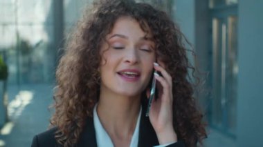 Kapalı kapılar ardında sokakta yürüyen neşeli beyaz kız cep telefonuyla konuşuyor iş ortağıyla konuşuyor gülümseyen iş kadını müdürüyle konuşuyor şehirde akıllı telefon konuşuyor.