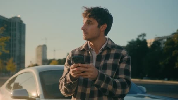 白人商人用智能手机应用聊天冲浪手机站在豪华轿车旁快乐的30多岁的年轻人开车在阳光城市现代技术和城市生活方式中开车 — 图库视频影像