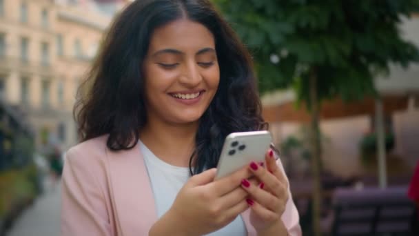 快乐笑着肖像画印度阿拉伯裔女学生女学生女商人走在城市大街上看书拿着手机在线聊天 — 图库视频影像