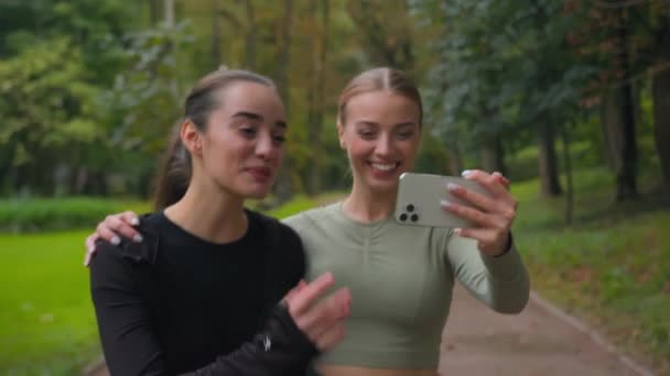 在公园里散步的快乐女孩白种人运动女性在公园里散步年轻女性博客与手机摄像头交谈智能手机通讯记录视频博客健康的生活方式运动博客户外运动日志 — 图库视频影像