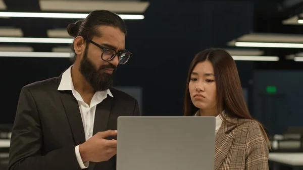 Indian businessman boss leader reprimanding Korean female Asian sad upset worker woman failure showing online mistake bad work result dissatisfied with laptop talk office diverse business colleagues