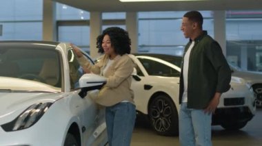 Mutlu çift Afro-Amerikan kadın erkek galeride otomobil seçen yeni araba sahipleri gülümseyen koca karısı araba galerisinde alışveriş yapan sevgili için sürpriz yaptı.
