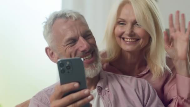 笑顔のコーカサスハッピーファミリーカップル男女祖母は 携帯アプリケーションを使用して携帯電話でビデオ通話を介して話し スマートフォン経由のオンライン会議リモートミーティングで通信 — ストック動画
