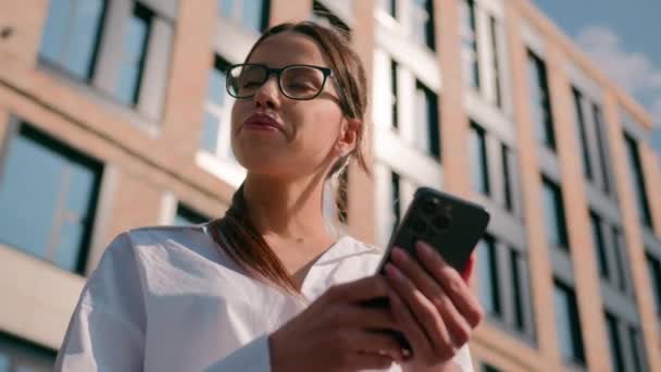 広く思慮深い女性の女ビジネスマンビジネス女性は 街で屋外を考える ポンダープラン ノード 承認で頭を書く スマートフォンを使用してワークスペースを整理する携帯電話上のプランナーで考える — ストック動画
