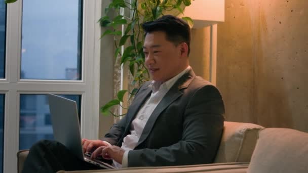 アジア人男性韓国人中年のビジネスマンは 高層ビルのオフィス会社の幸せな起業家雇用主のコンピュータ笑顔でノートパソコンのライティングビジネスプロジェクトにタイピングするリモートインターネットを働いています — ストック動画