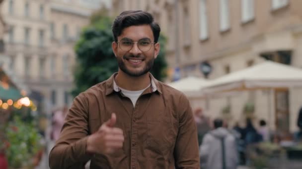幸せな喜びの若い笑顔のインドのアラビアの民族の男性顧客の顧客の学生のビジネスマンショーのような手親指のジェスチャーの良い結果優秀な同意は屋外のシンボルを承認することをお勧めします都市の通り — ストック動画