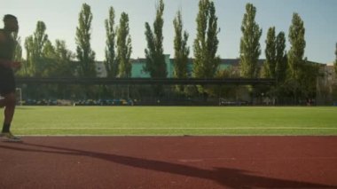 Afro-Amerikalı koşucu koşucu atlet, şehir stadyumunda yüksek bacaklar üzerinde koşuyor sabah aktivitesi koşuyor aktif kardiyo sporu yapıyor yarış pistinde koşan sporcu erkek triatloncu.
