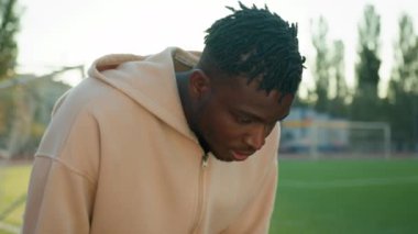 Afrika kökenli Amerikalı sporcu terleyerek sabah sporunu durdurdu. Stadyumda antrenman yaptı. Yorgun yüzlü sporcu yoruldu.