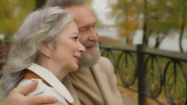 愛で引退したカップルを閉じる 歳の家族笑顔のリラックスした祖父母は 秋の公園で一緒に座って幸せな白人女性男は 祖母と祖父を結びつけて街の外でリラックス — ストック動画
