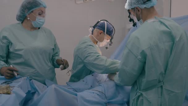 外科医生与辅助男医生一起为病人施行外科手术 用医疗器械切除阑尾炎 恶性肿瘤 心脏病等并发症的护士站在桌旁 — 图库视频影像