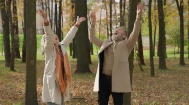 Mutlu, yaşlı, beyaz, olgun bir çift. 60 'lı yaşlarda, yaşlı bir adam. Büyükannesi ve büyükbabası, sonbahar parkında yapraklarını birlikte atarak çocukluklarına geri dönüyorlar.