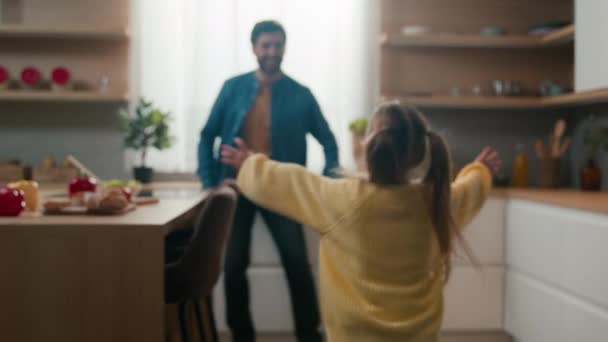 白种人快乐的家庭在厨房里小女孩跑着跑着去找可爱的爸爸爸爸抱着女儿站起来轮流在家里做饭早上见面爱抚孩子 — 图库视频影像