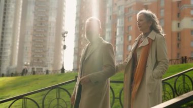 Yaşlı zengin çift mutlu aile olgun kadın adam şehirde yürüyor modern şehir konutları gökdelenler olgun 60 'lı yaşlarda orta yaşlı eşler birlikte yürüyorlar şık kıyafetler giyiyorlar