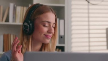 Beyaz kadın gülümseyen öğrenci kız işkadını iş kadını ofis kütüphanesinde bilgisayarla çalışan iş kadını kulaklık takıyor müzik dinliyor ve müzik dinleniyor.