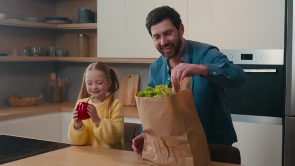 快乐的家庭白种人父亲与小女孩一起拆包购物可重复使用的生态包小女儿帮爸爸拆包红辣椒面包西红柿蔬菜订购食物 — 图库视频影像