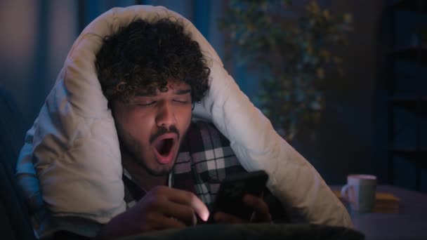 アラビア人は携帯電話の不眠症の夜を使用して疲れ切った男 インドの男疲れた 疲れた 毛布の下 ソーシャルメディアアプリ スマートフォンの眠れない中毒をスクロール悪い習慣 — ストック動画